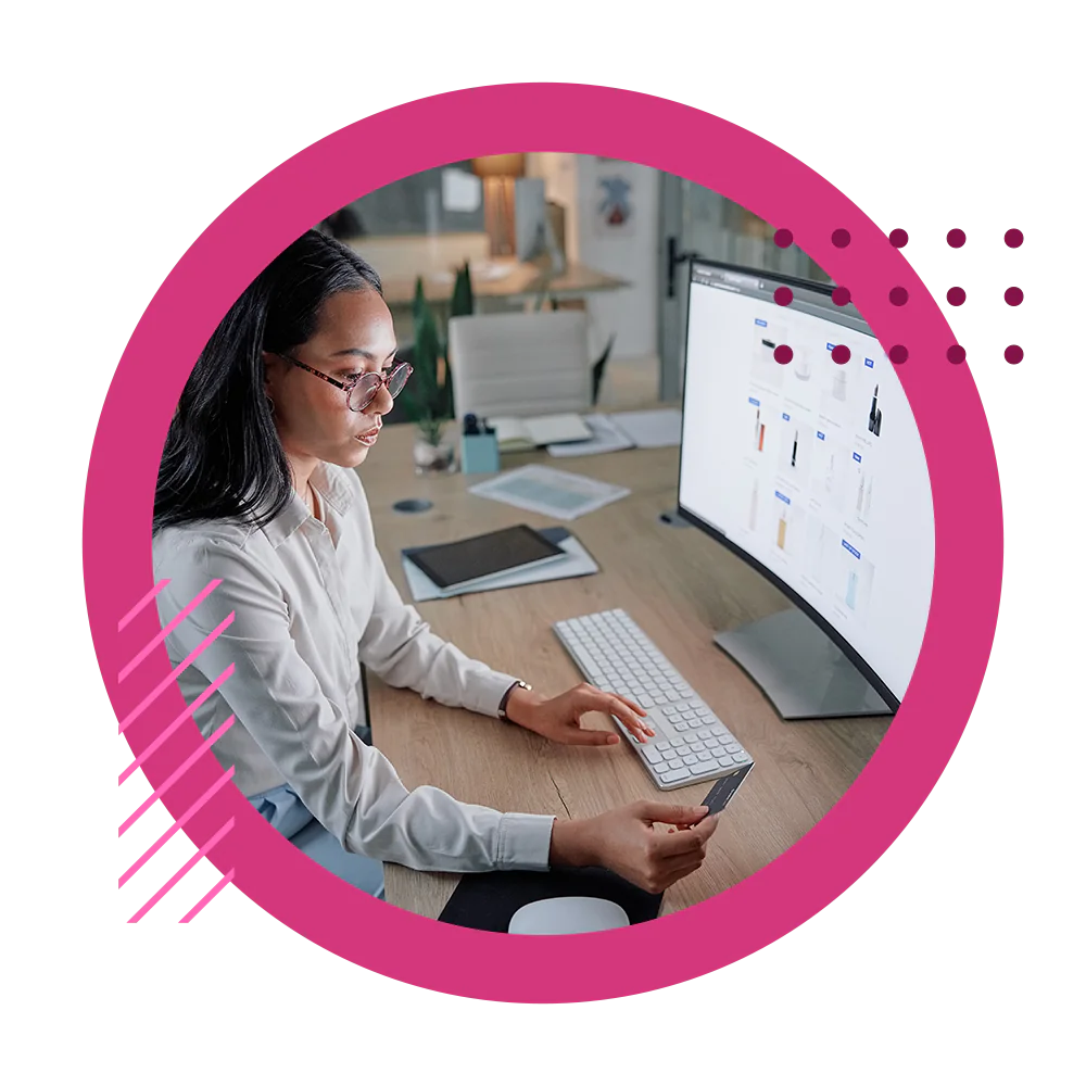 A business woman looking at her credit card to make a purchase at her desktop monitor on a B2B ecommerce website.
