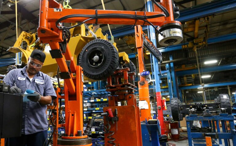 Jorge Morales prepares paperwork as he works on an assembly line constructing forklifts, at a Mitsubishi Caterpillar Forklift America Inc. factory